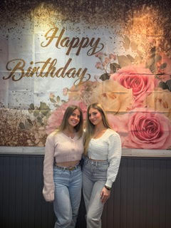 The two owners of the Cloud Nine Events business in front of a festive background décor.
